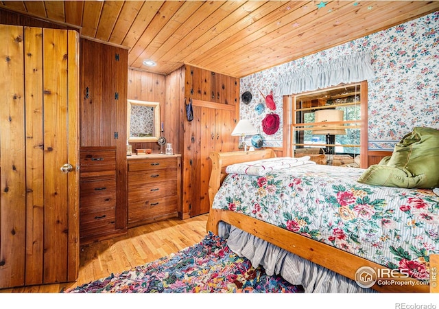 bedroom with wood ceiling, wooden walls, and light hardwood / wood-style flooring