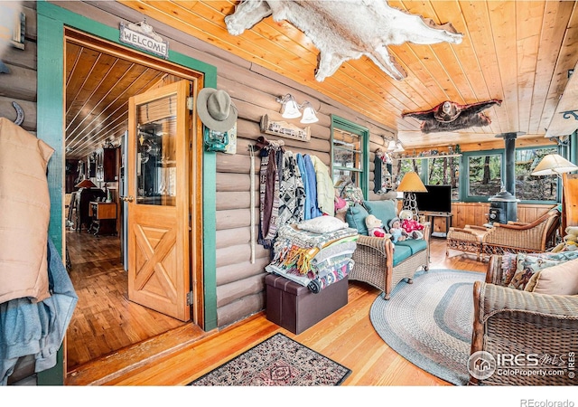 living room with a wood stove, log walls, hardwood / wood-style flooring, and wood ceiling