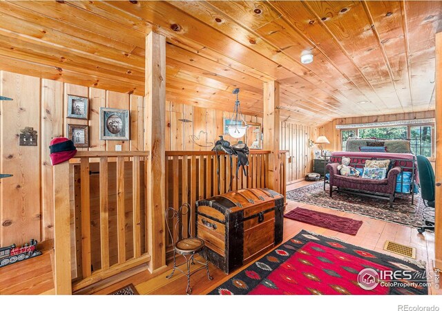 bedroom featuring wooden walls, vaulted ceiling, and wood-type flooring