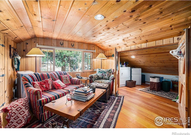 living room with wood walls, light wood-type flooring, washing machine and dryer, wood ceiling, and lofted ceiling