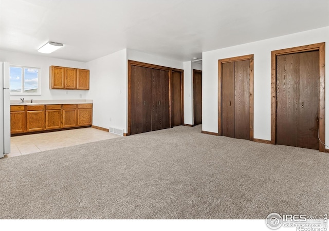 unfurnished bedroom featuring light colored carpet and multiple closets