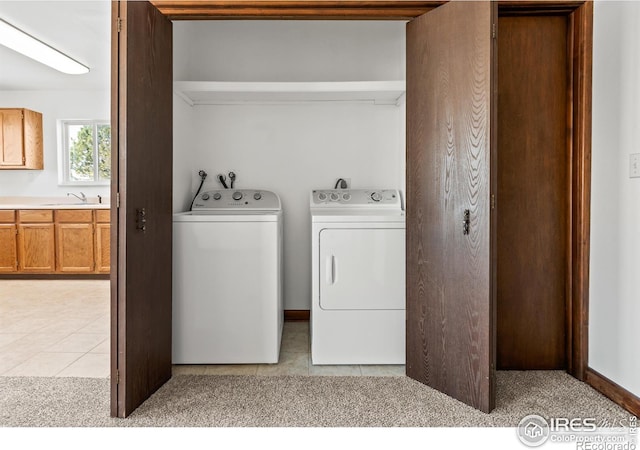 laundry room with washing machine and clothes dryer, sink, and light tile patterned flooring