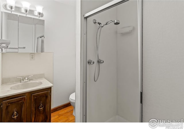 bathroom featuring vanity, wood-type flooring, an enclosed shower, and toilet