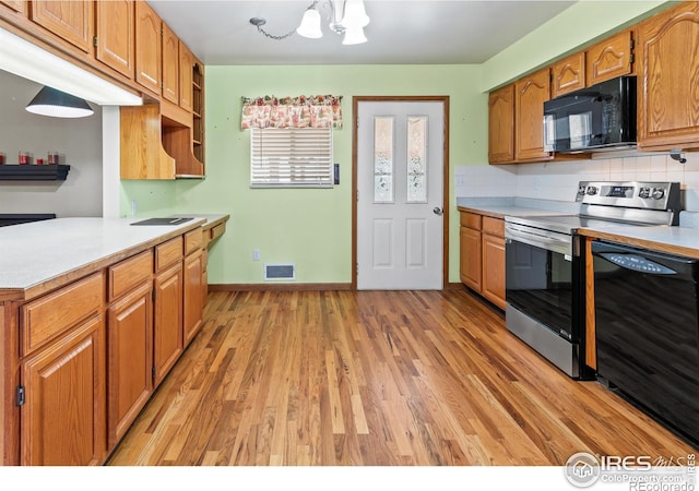 kitchen featuring backsplash, light hardwood / wood-style floors, an inviting chandelier, and black appliances