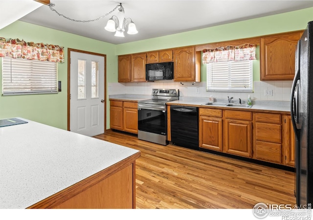 kitchen with black appliances, light hardwood / wood-style flooring, a wealth of natural light, and a chandelier