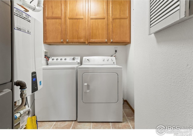 laundry area with washing machine and dryer, light tile patterned floors, and cabinets