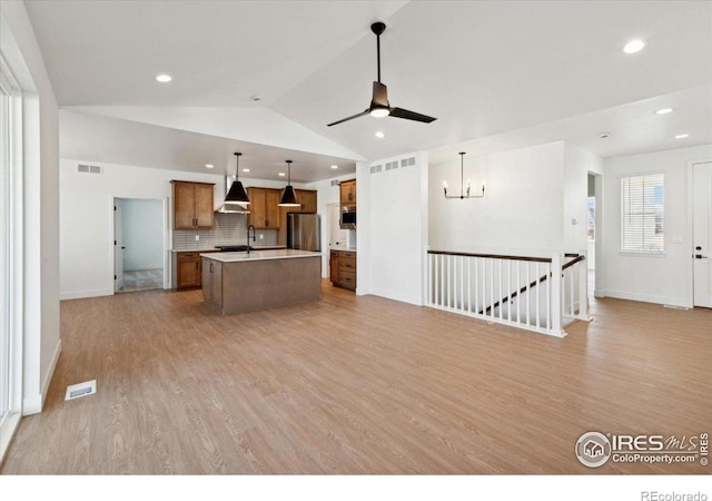 kitchen featuring wall chimney exhaust hood, stainless steel appliances, pendant lighting, a kitchen island, and lofted ceiling