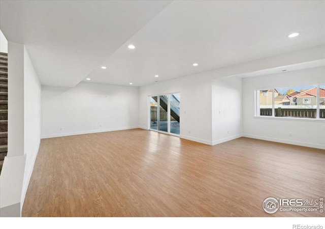 unfurnished living room featuring plenty of natural light and light hardwood / wood-style floors