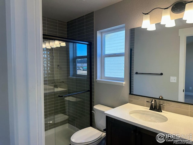 bathroom featuring vanity, toilet, and a shower with shower door