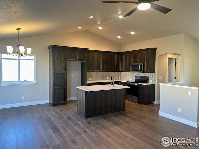 kitchen with lofted ceiling, dark wood-type flooring, an island with sink, appliances with stainless steel finishes, and tasteful backsplash