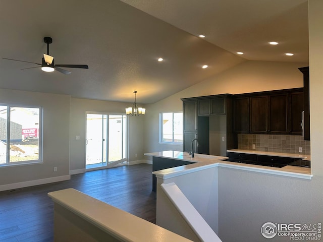 kitchen with dark hardwood / wood-style flooring, vaulted ceiling, decorative backsplash, black electric stovetop, and ceiling fan with notable chandelier