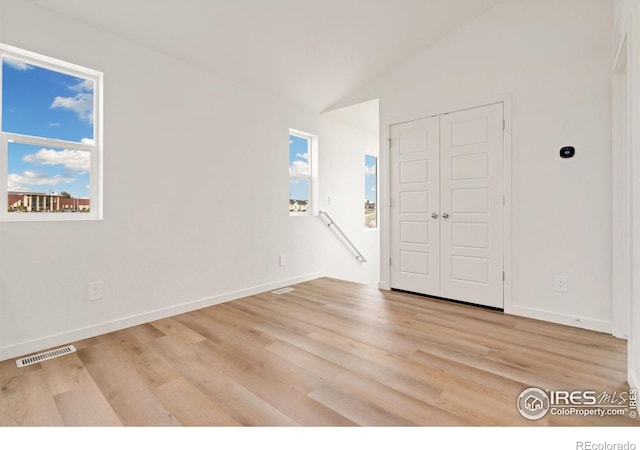 spare room with light hardwood / wood-style floors and vaulted ceiling