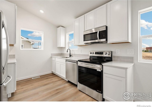 kitchen with sink, white cabinets, stainless steel appliances, and a healthy amount of sunlight