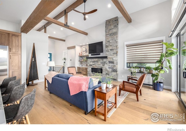 living room featuring beam ceiling, a fireplace, ceiling fan, and light hardwood / wood-style flooring