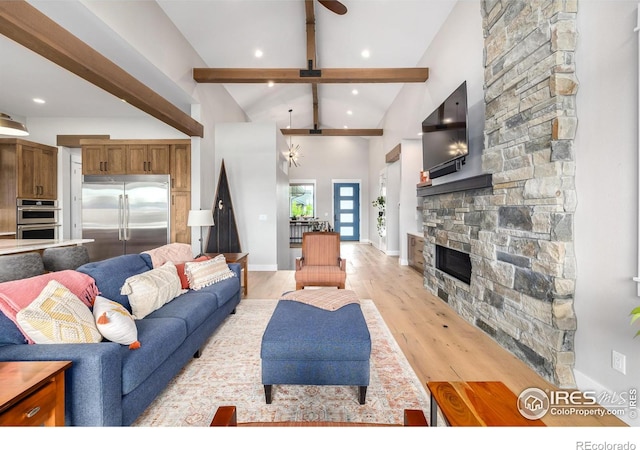 living room featuring a stone fireplace, ceiling fan, vaulted ceiling with beams, and light wood-type flooring