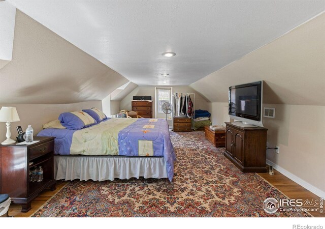 bedroom featuring dark wood-type flooring, a textured ceiling, and lofted ceiling