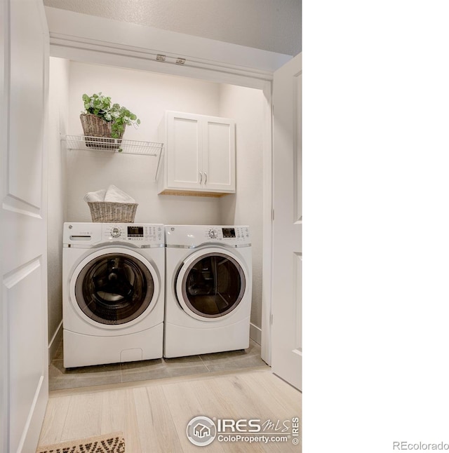 laundry room featuring cabinets, washer and dryer, and light hardwood / wood-style floors