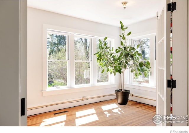 interior space featuring light wood-type flooring, a baseboard heating unit, and plenty of natural light