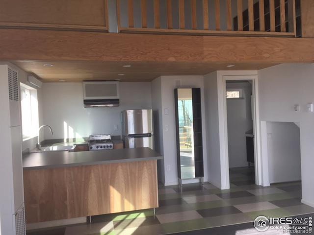 kitchen with dark tile floors, sink, stainless steel refrigerator, and stove