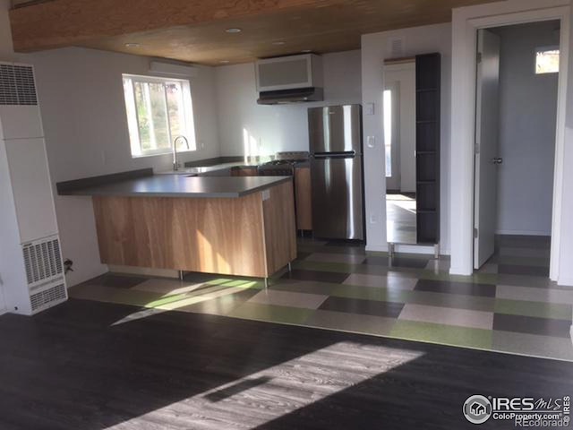 kitchen with dark hardwood / wood-style floors, sink, kitchen peninsula, and stainless steel refrigerator