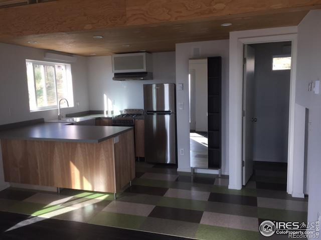 kitchen featuring sink, stainless steel refrigerator, kitchen peninsula, and dark tile floors