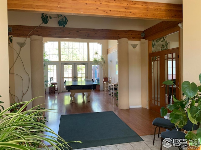 interior space with decorative columns, light hardwood / wood-style floors, beamed ceiling, and french doors