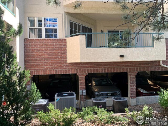 view of home's exterior with brick siding, cooling unit, and a balcony