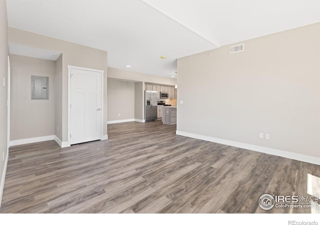 unfurnished living room featuring electric panel, visible vents, baseboards, and wood finished floors