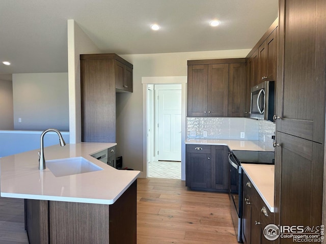 kitchen featuring decorative backsplash, dark brown cabinets, sink, light hardwood / wood-style flooring, and range with electric stovetop