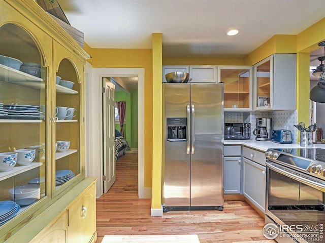 kitchen with decorative backsplash, stainless steel appliances, light hardwood / wood-style flooring, and gray cabinetry