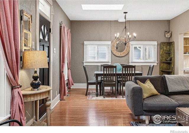 dining room with a skylight, an inviting chandelier, and light hardwood / wood-style floors