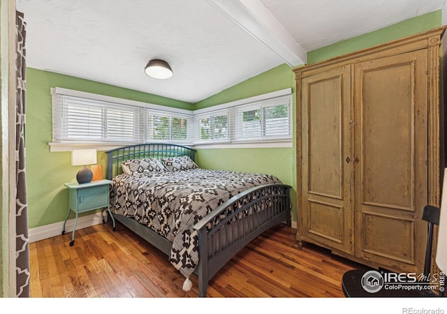 bedroom with lofted ceiling with beams and dark wood-type flooring