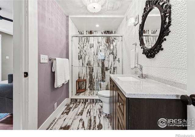 bathroom featuring vanity, a shower with shower door, and toilet