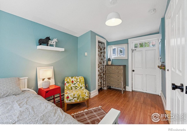 bedroom featuring a closet, hardwood / wood-style floors, and a baseboard radiator