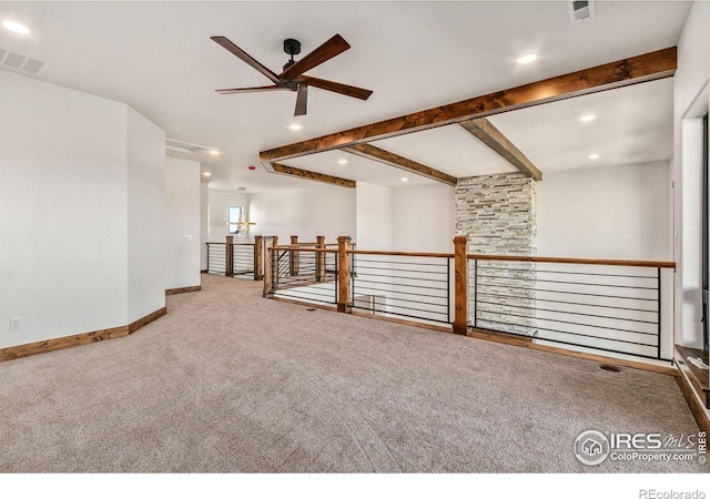 unfurnished living room featuring beamed ceiling, ceiling fan, and carpet flooring