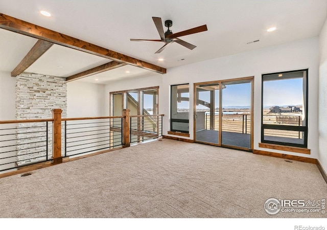 empty room with ceiling fan, carpet flooring, and beam ceiling