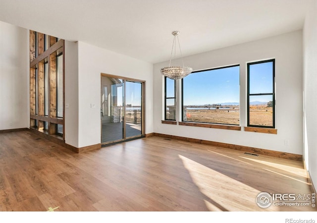 unfurnished dining area with an inviting chandelier, hardwood / wood-style floors, and a wealth of natural light