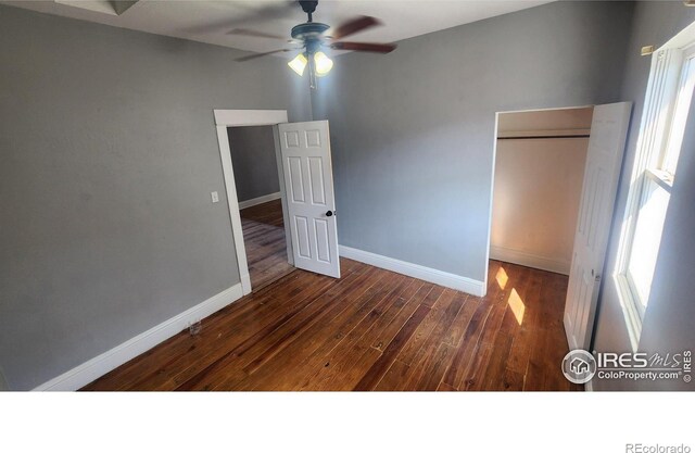 unfurnished bedroom featuring ceiling fan, a closet, and dark wood-type flooring