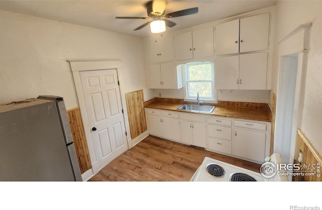 kitchen with stainless steel fridge, white cabinets, ceiling fan, light hardwood / wood-style flooring, and sink