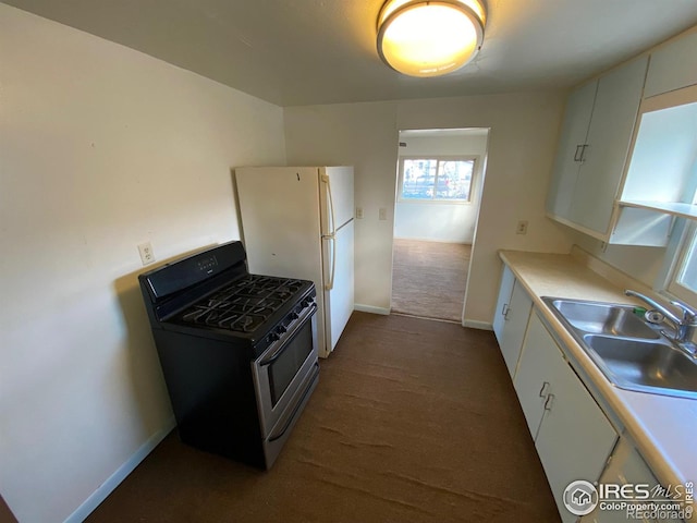 kitchen featuring dark carpet, sink, white refrigerator, black gas stove, and white cabinetry