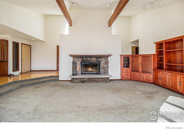 unfurnished living room with beam ceiling, light colored carpet, a fireplace, and high vaulted ceiling