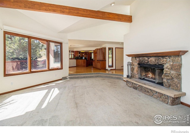 unfurnished living room with beamed ceiling, a stone fireplace, light colored carpet, and high vaulted ceiling