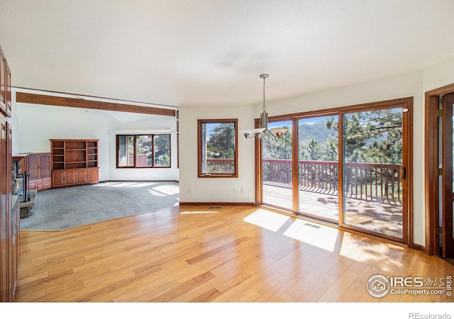 unfurnished living room featuring light hardwood / wood-style flooring and an inviting chandelier