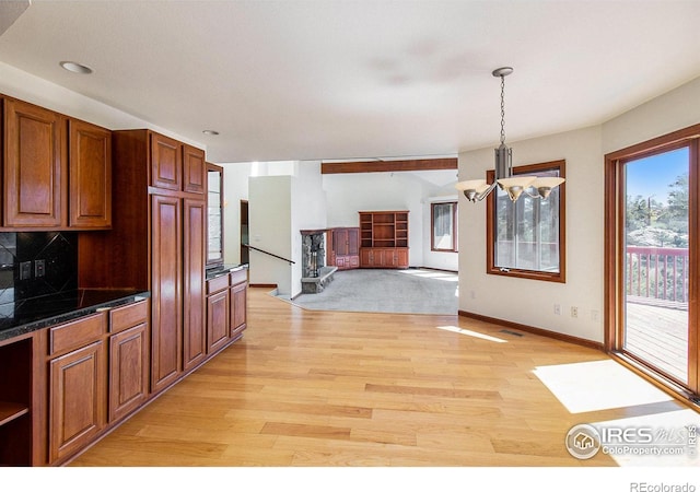 kitchen featuring pendant lighting, light hardwood / wood-style floors, backsplash, and a chandelier