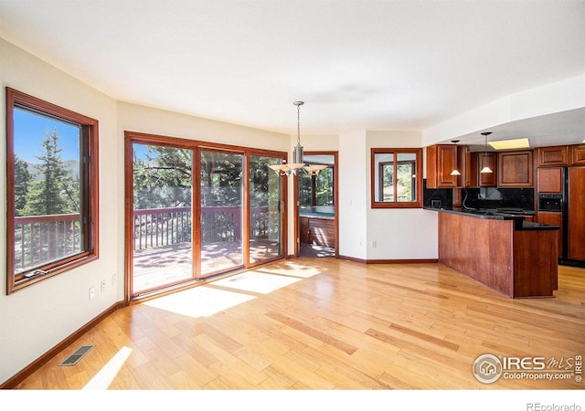 kitchen with decorative light fixtures, paneled built in refrigerator, and light hardwood / wood-style flooring