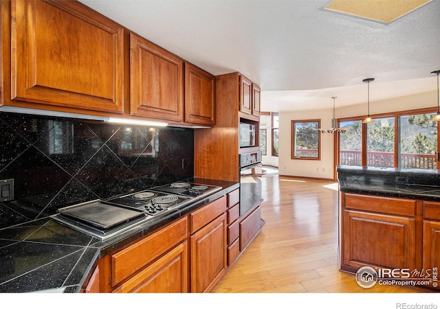 kitchen featuring decorative backsplash, light wood-type flooring, stainless steel appliances, and a chandelier