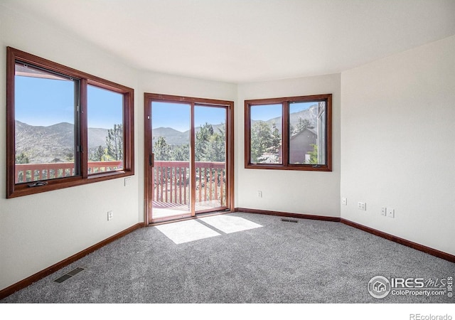 carpeted spare room featuring a mountain view and a healthy amount of sunlight