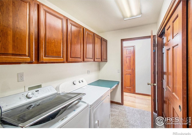 laundry area featuring cabinets, light hardwood / wood-style floors, and washer and clothes dryer