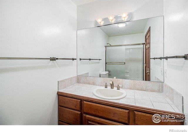 bathroom with vanity, a shower with shower door, and toilet