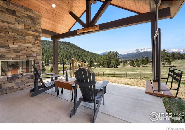 view of patio / terrace with a mountain view and an outdoor stone fireplace